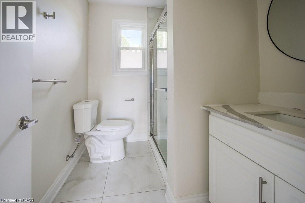 Bathroom featuring a glass-enclosed shower, white vanity with an integrated sink and stone countertop, and large format tile flooring - 33 Sixth Avenue Unit# Upper, Kitchener, ON - Indoor Photo Showing Bathroom