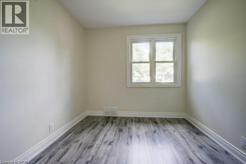 Room featuring wood-finish flooring, light-toned walls, and a white-framed window - 33 Sixth Avenue Unit# Upper, Kitchener, ON - Indoor Photo Showing Other Room