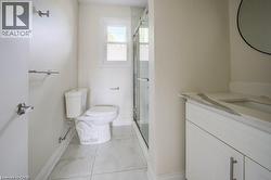 Bathroom featuring a glass-enclosed shower, white vanity with an integrated sink and stone countertop, and large format tile flooring -