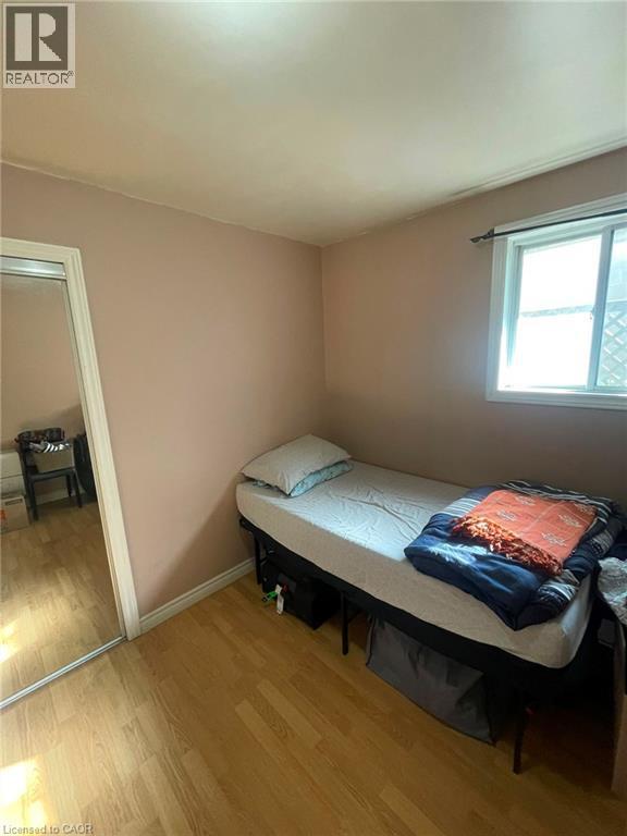 Room featuring wood-finish flooring, a white window frame, and a mirrored closet door - 267 Mackie Place Unit# 2, Kitchener, ON - Indoor Photo Showing Bedroom