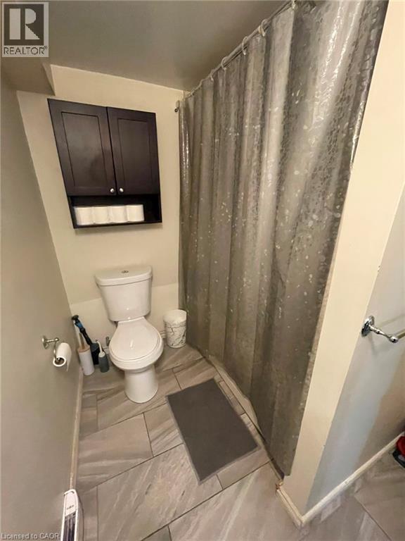 Bathroom featuring a built-in shower area, a white toilet, and dark wood-finish wall cabinetry - 267 Mackie Place Unit# 2, Kitchener, ON - Indoor Photo Showing Bathroom