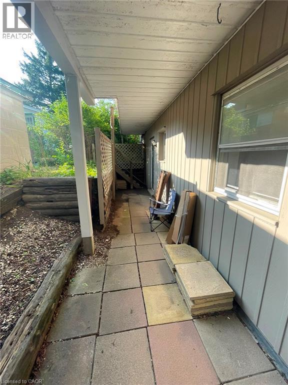 Covered side patio featuring square paver flooring, vertical siding, and a partial lattice fence - 267 Mackie Place Unit# 2, Kitchener, ON - Outdoor With Exterior