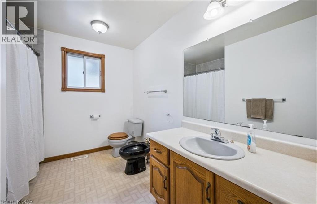 Bathroom with a wood-finish vanity, integrated white sink, and a large wall-mounted mirror - 42 Azores Crescent, Cambridge, ON - Indoor Photo Showing Bathroom