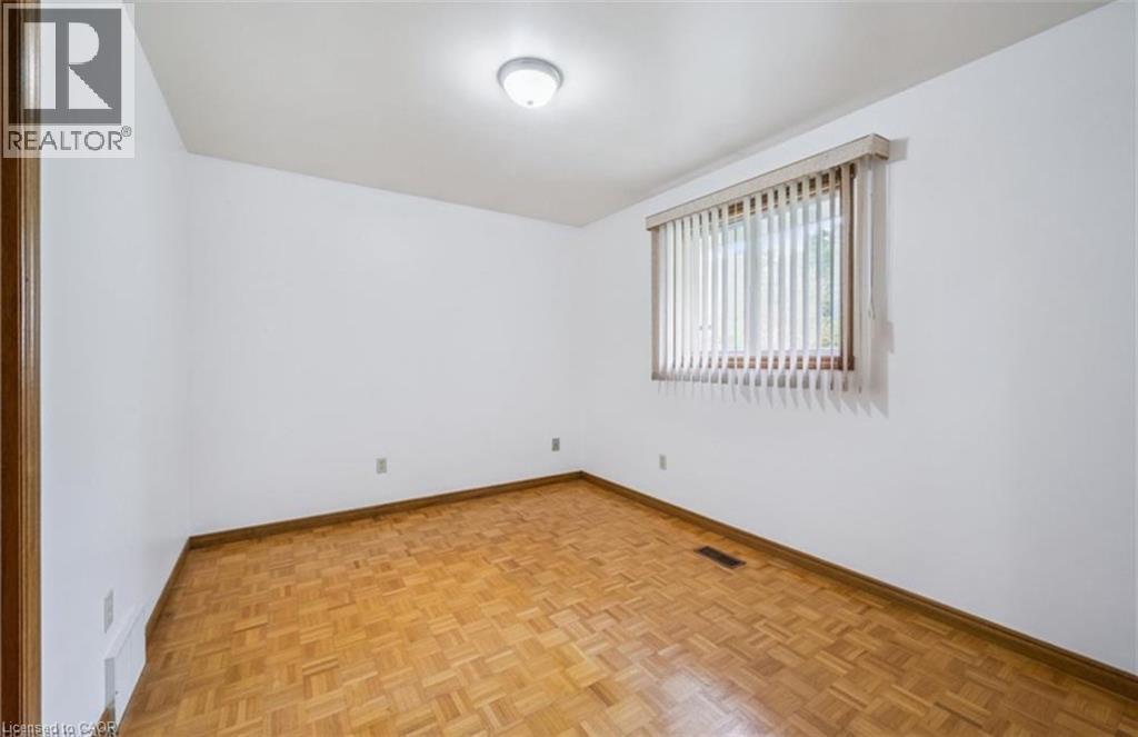 Room featuring wood-finish parquet flooring, white painted walls, and a window with vertical blinds - 42 Azores Crescent, Cambridge, ON - Indoor Photo Showing Other Room