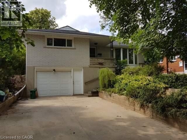 Split-level residence featuring light-colored brick siding and a dark-shingle roof - 48 Austin Drive Unit# Upper, Waterloo, ON - Outdoor