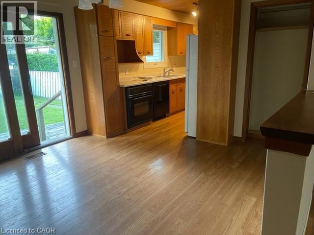 Kitchen featuring wood-finish flooring, light-toned cabinetry, light countertops, and a black oven - 48 Austin Drive Unit# Upper, Waterloo, ON - Indoor