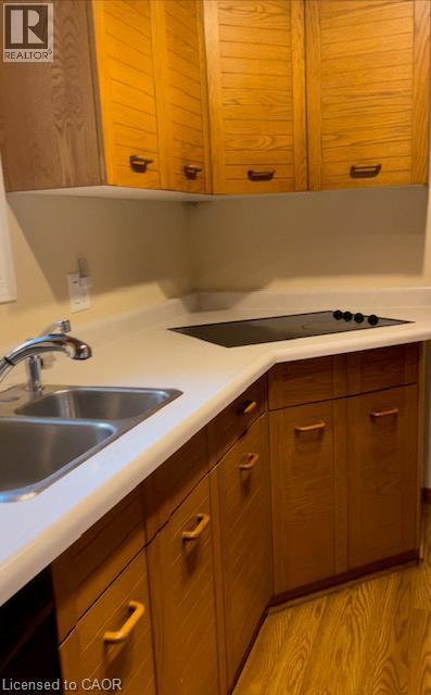 Kitchen featuring wood-finish cabinetry, solid surface countertops, a stainless steel double basin sink with chrome faucet, and a built-in electric cooktop - 48 Austin Drive Unit# Upper, Waterloo, ON - Indoor Photo Showing Kitchen With Double Sink