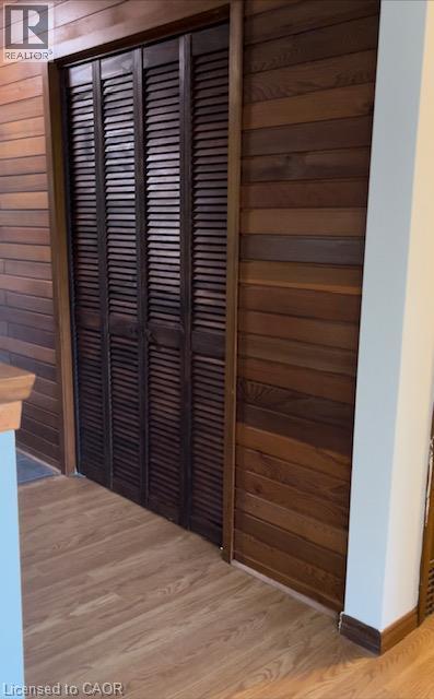 Louvered bi-fold doors framed by horizontal wood paneling and wood-finish flooring - 48 Austin Drive Unit# Upper, Waterloo, ON - Indoor Photo Showing Other Room