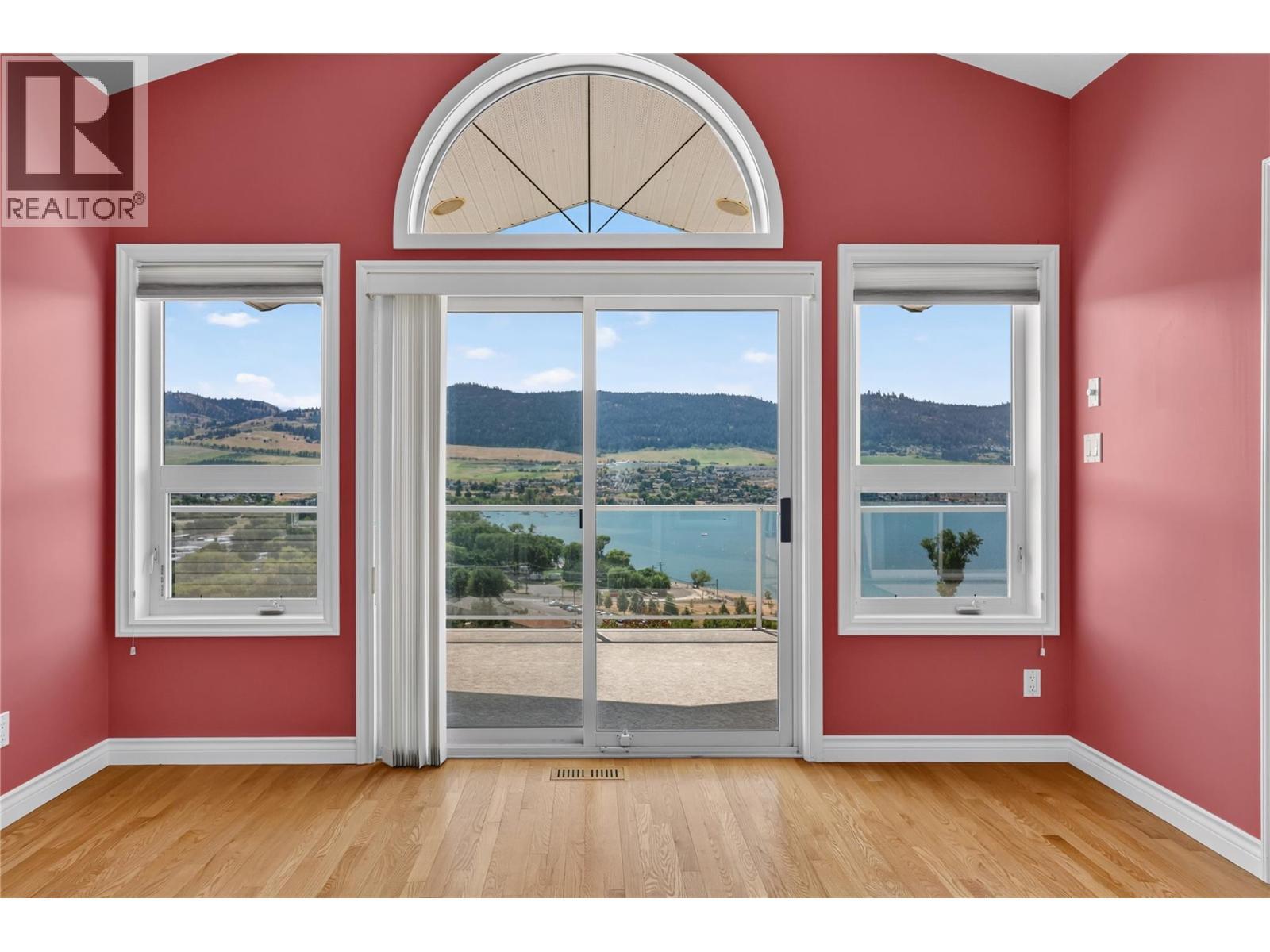 Large windows to take in the views. - 7083 Jasper Drive, Vernon, BC - Indoor Photo Showing Other Room With Body Of Water