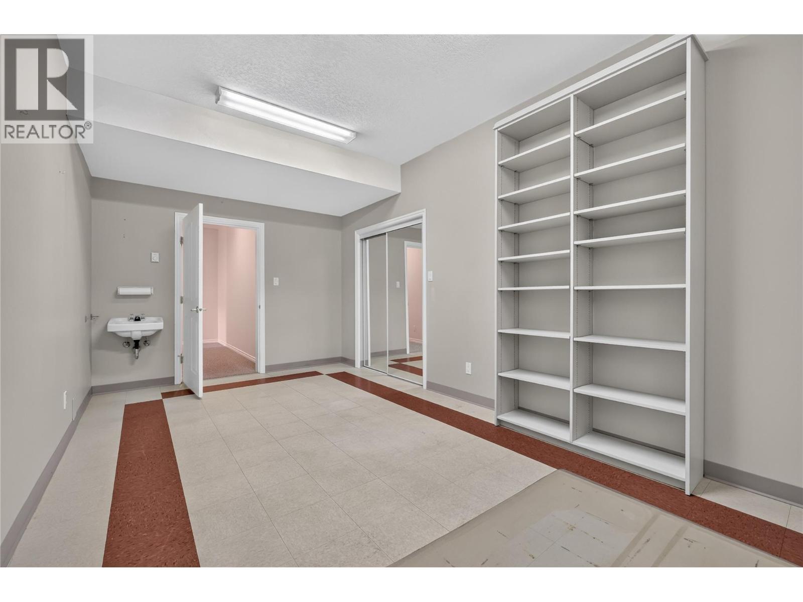 Lower level bedroom. The perfect space for a home-based business. With utility sink, extensive built-in shelving, and ample workspace. - 7083 Jasper Drive, Vernon, BC - Indoor Photo Showing Other Room