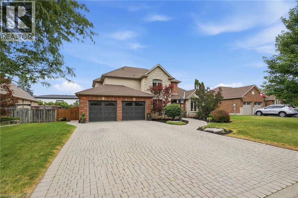 4 car Driveway. Exterior featuring a stone and brick facade, two-car garage with carriage-style doors, paver driveway, manicured landscaping, and mature foliage - 5 Manor Crescent, Grimsby, ON - Outdoor
