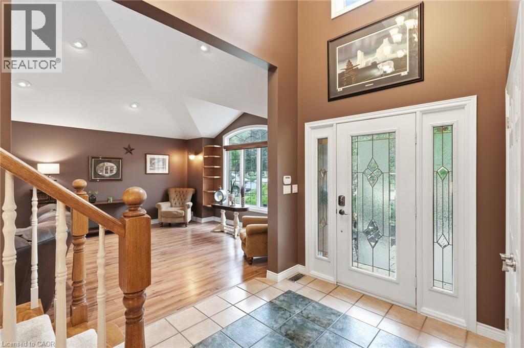 Foyer featuring a decorative glass front door with sidelights, complemented by a tiled entry and wood-finish flooring - 5 Manor Crescent, Grimsby, ON - Indoor Photo Showing Other Room