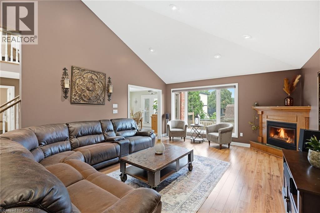 Spacious living area featuring a vaulted ceiling with recessed lighting, wood-finish flooring, a wood-mantel fireplace, and a large picture window - 5 Manor Crescent, Grimsby, ON - Indoor Photo Showing Living Room With Fireplace