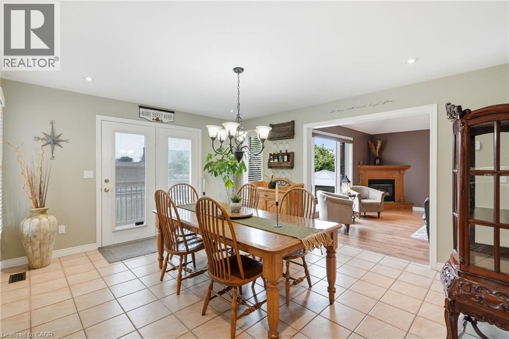 Light-toned tile flooring in a dining area featuring white double patio doors, recessed lighting, and a multi-bulb chandelier - 5 Manor Crescent, Grimsby, ON - Indoor Photo Showing Dining Room