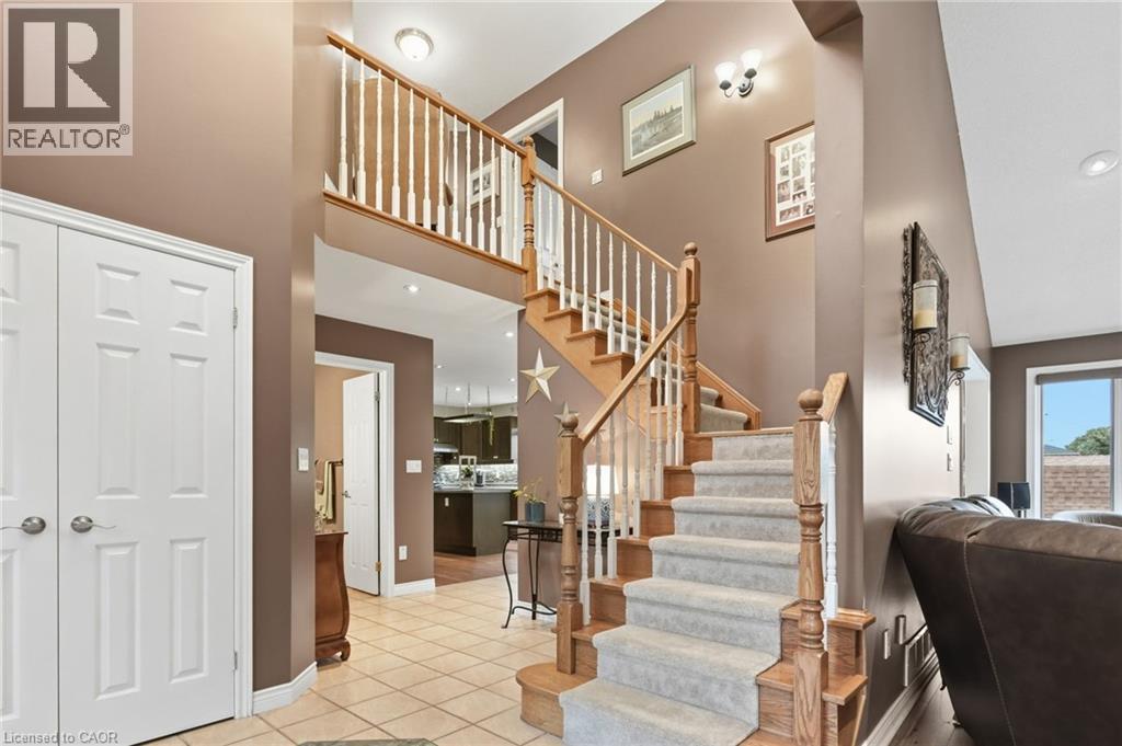 Two-story foyer featuring a staircase with wood-finish handrails and carpeted treads, tile flooring, and white paneled doors - 5 Manor Crescent, Grimsby, ON - Indoor Photo Showing Other Room