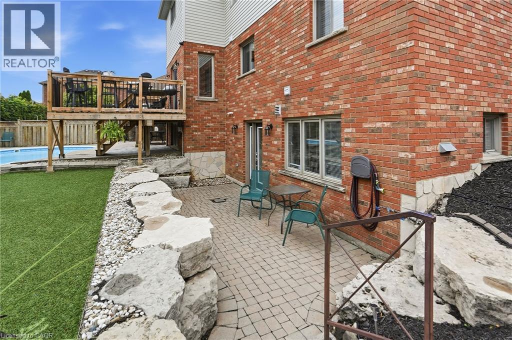 Outdoor living space featuring a brick exterior, paver patio, stone retaining wall, and a raised wooden deck - 5 Manor Crescent, Grimsby, ON - Outdoor With Deck Patio Veranda With Exterior