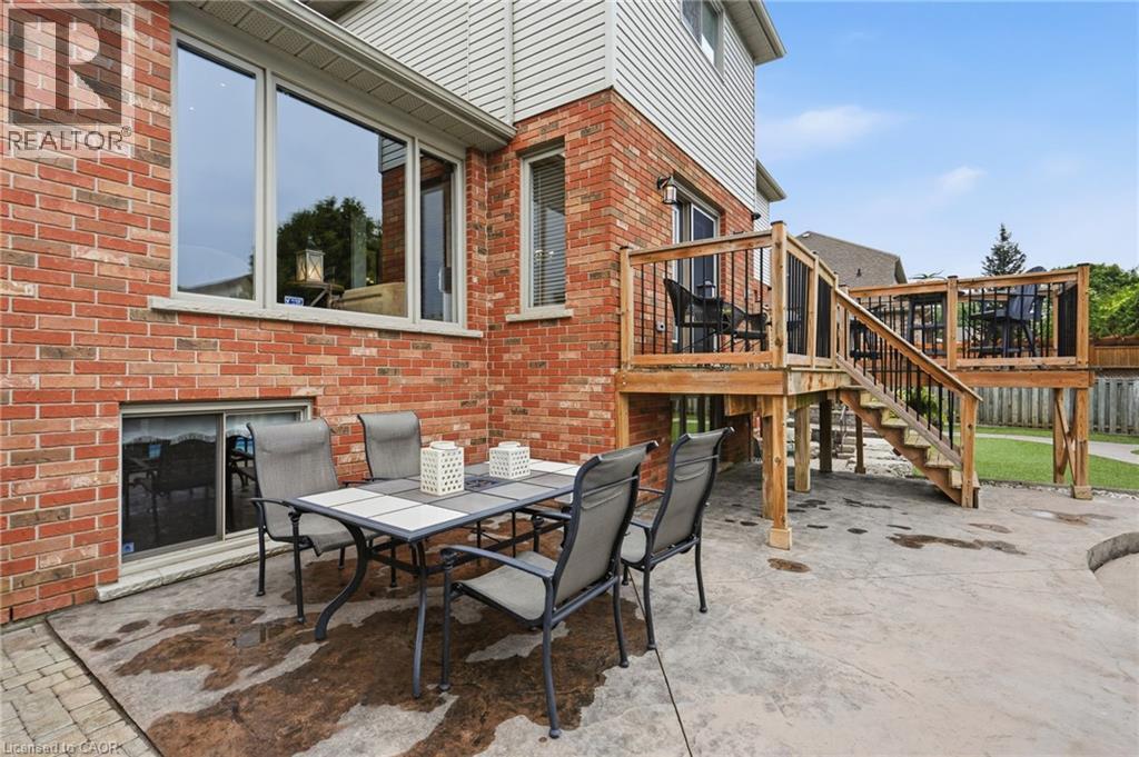 Multi-level wooden deck with black balusters, brick exterior, and a lower-level concrete patio - 5 Manor Crescent, Grimsby, ON - Outdoor With Deck Patio Veranda With Exterior