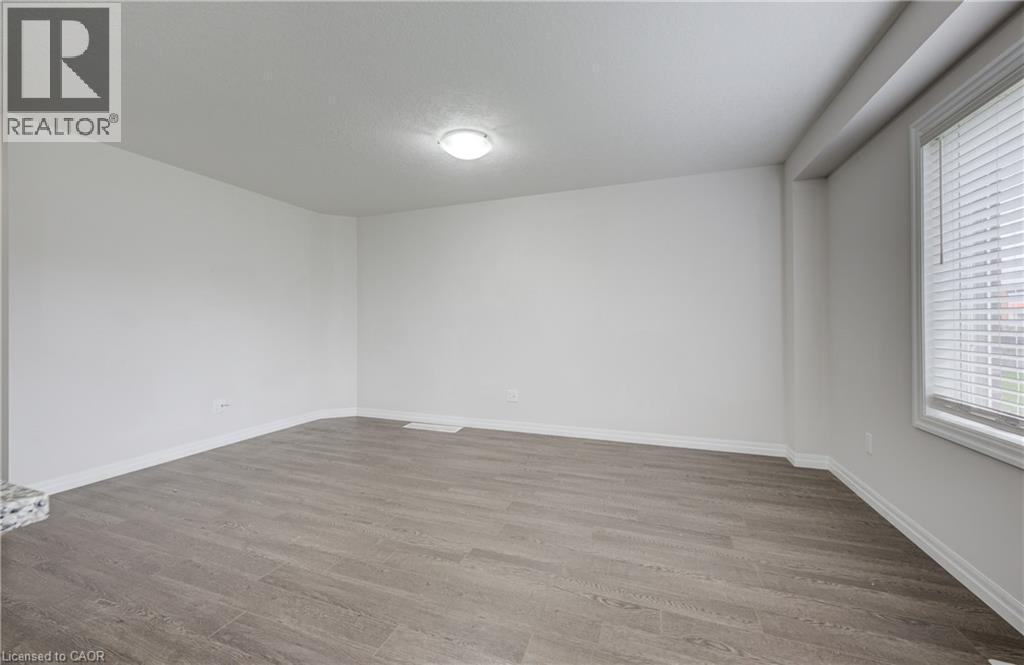 Spacious room featuring light gray wood-finish flooring, white walls, and a recessed ceiling light fixture - 823 Paris Boulevard, Waterloo, ON - Indoor Photo Showing Other Room