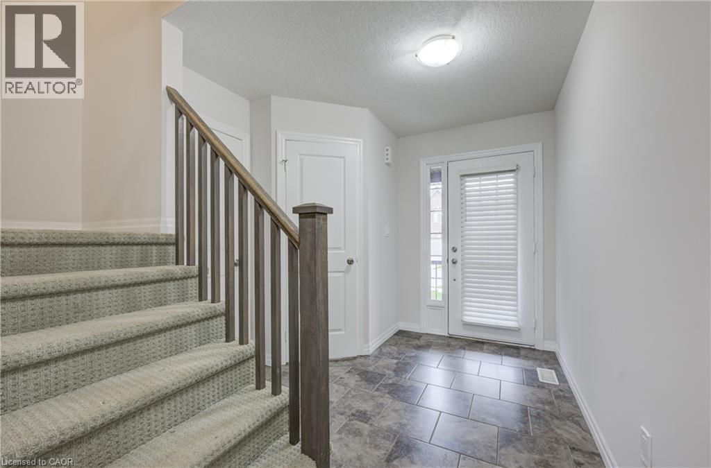 Foyer with ceramic tile flooring, a white exterior door with an integrated blind, and a staircase featuring carpeted treads and a wood-finish railing - 823 Paris Boulevard, Waterloo, ON - Indoor Photo Showing Other Room