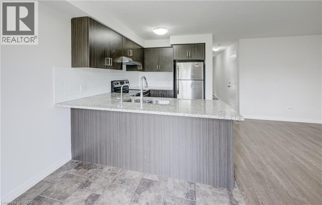 Modern kitchen featuring wood-finish cabinetry, stainless steel appliances, a white subway tile backsplash, and a light-toned countertop with an integrated sink - 823 Paris Boulevard, Waterloo, ON - Indoor Photo Showing Kitchen With Double Sink