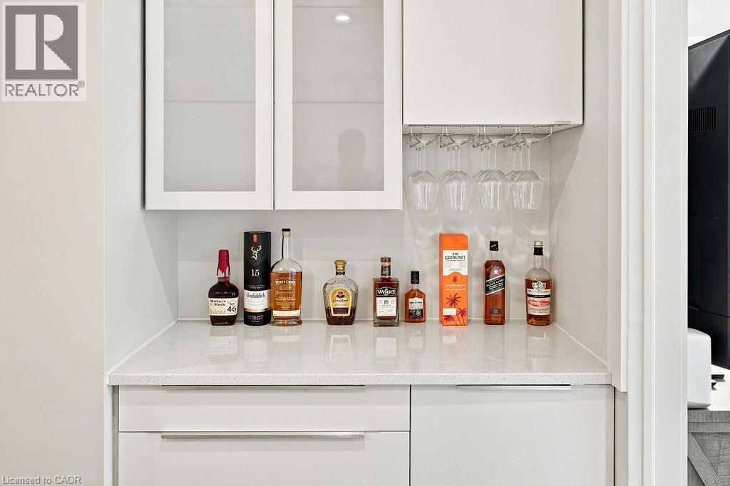 Built-in wet bar featuring white cabinetry, frosted glass cabinet doors, a light-toned countertop, and integrated stemware storage - 67 Weber Street S, Waterloo, ON - Indoor Photo Showing Other Room