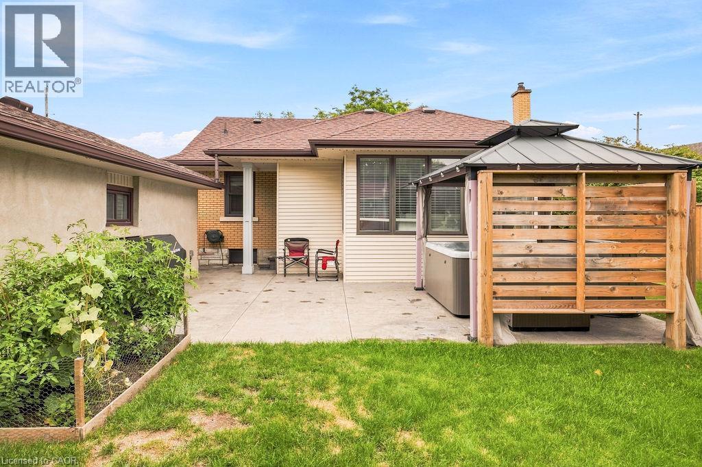 Expansive concrete patio area featuring a built-in gazebo with slatted wood privacy screens and a hot tub - 67 Weber Street S, Waterloo, ON - Outdoor