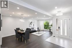 Open-concept living space featuring recessed lighting, dark wood-finish flooring, a curved bay window, and a white front entry door with sidelights - 