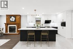 Modern kitchen featuring a large island with a light-toned countertop, white glossy cabinetry, and integrated black appliances - 