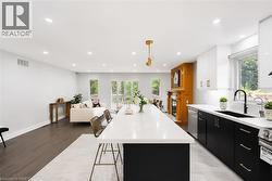 Modern kitchen featuring a large island with white countertop, black base cabinetry, and brass hardware - 