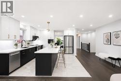Contemporary kitchen featuring a large central island, white countertops, and a black and white cabinet scheme - 