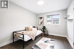 Bright interior room featuring a window with a white frame, dark wood-finish flooring, and light gray walls - 