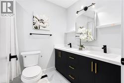Dual vanity with black cabinetry, gold hardware, and white countertops - 