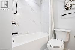 Alcove bathtub with marble-look wall tiling and matte black fixtures - 