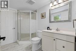 Bathroom featuring a corner shower with glass enclosure, single vanity with white countertop, chrome faucet, and a framed mirror - 