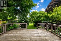 Expansive wood deck with baluster railings opening to a landscaped backyard - 