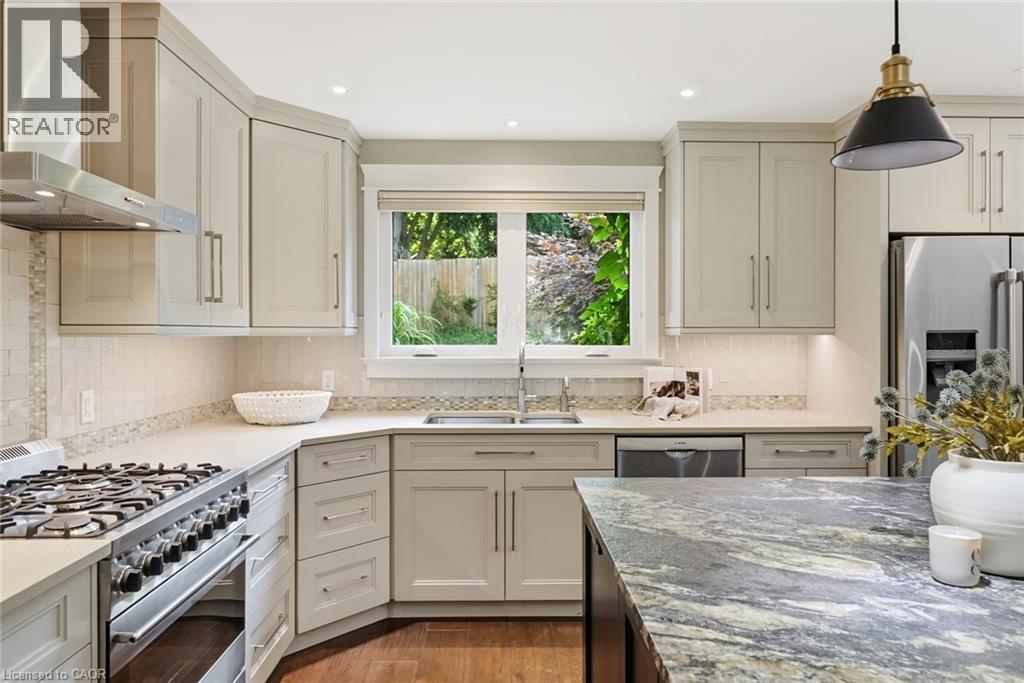 Contemporary kitchen featuring light-toned cabinetry, stainless steel appliances, a gas range with an overhead ventilation hood, a double basin sink, and a multi-toned island countertop - 266 Ferndale Place, Waterloo, ON - Indoor Photo Showing Kitchen With Upgraded Kitchen