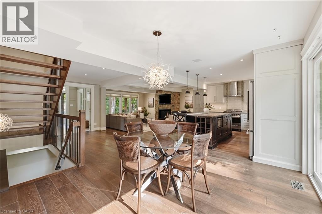 Open-concept main level featuring wood-finish flooring, a contemporary dining area with a glass-top table, and a tiered staircase with dark metal balusters - 266 Ferndale Place, Waterloo, ON - Indoor Photo Showing Other Room