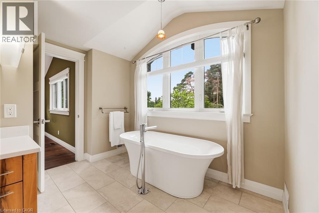 Freestanding soaking tub with floor-mounted faucet, set against a large arched picture window - 266 Ferndale Place, Waterloo, ON - Indoor Photo Showing Bathroom
