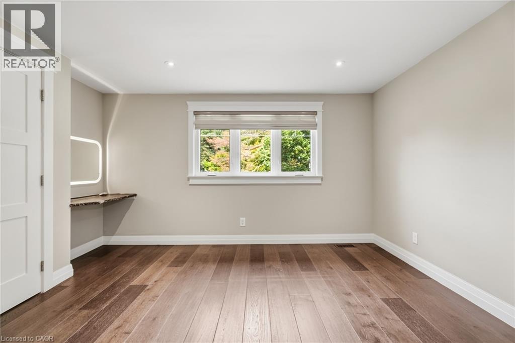 Hardwood flooring throughout, recessed ceiling lighting, and a built-in wood-finish desk with an illuminated mirror - 266 Ferndale Place, Waterloo, ON - Indoor Photo Showing Other Room
