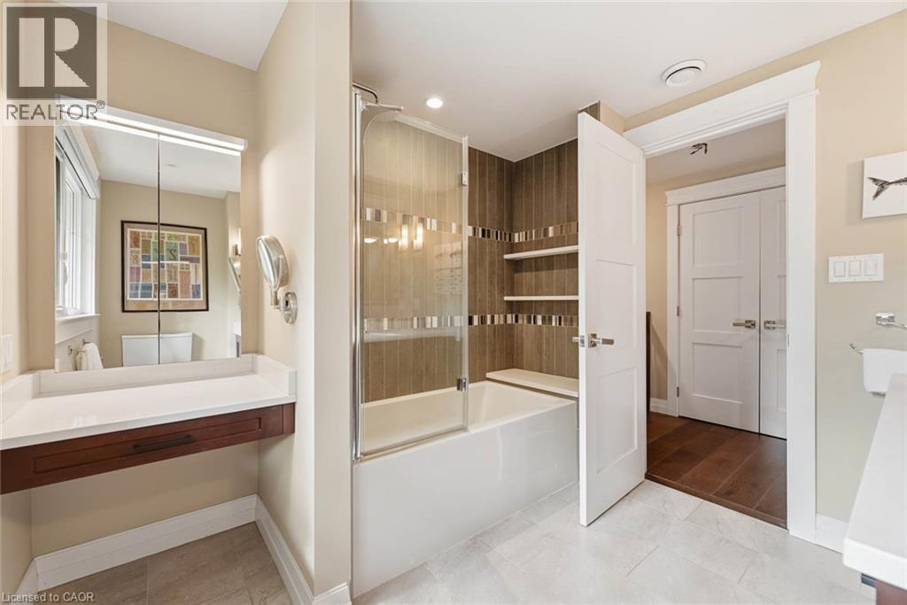 Full bathroom featuring a tub and shower combination with glass enclosure, integrated shelving, and vertical wood-finish wall tile accents - 266 Ferndale Place, Waterloo, ON - Indoor Photo Showing Bathroom