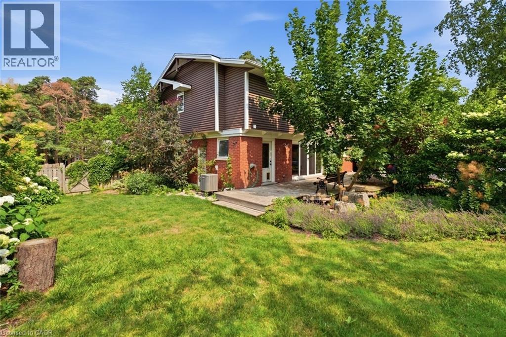 Expansive backyard featuring a manicured lawn, established landscaping, a multi-level wood deck, and mature perimeter trees - 266 Ferndale Place, Waterloo, ON - Outdoor