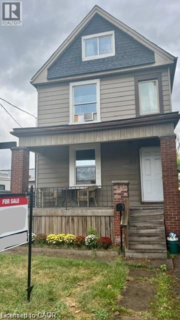 The property features a front porch with brick pillars and a white front door - 219 Avondale Street, Hamilton, ON - Outdoor With Deck Patio Veranda