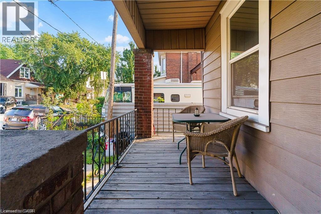 The property features a porch with wood decking and a black metal railing - 219 Avondale Street, Hamilton, ON - Outdoor With Exterior