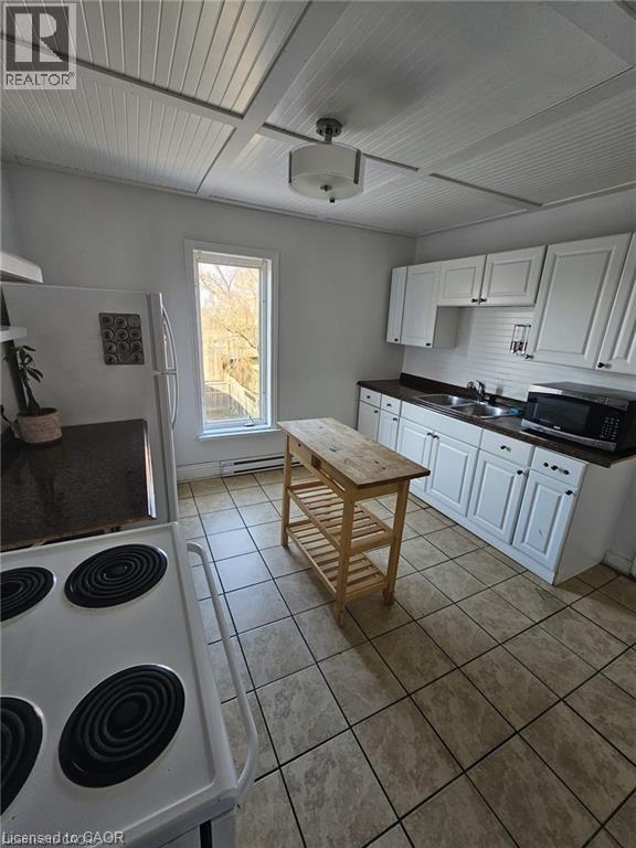 The kitchen features white cabinetry, a double basin sink, and tiled flooring - 219 Avondale Street, Hamilton, ON - Indoor Photo Showing Kitchen With Double Sink