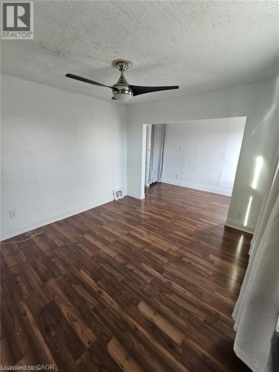 This room features dark wood-style flooring and a modern ceiling fan - 219 Avondale Street, Hamilton, ON - Indoor Photo Showing Other Room