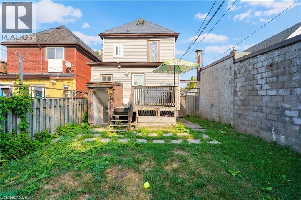 The property features a rear deck with access to the yard, which includes a lawn area and stepping stones - 219 Avondale Street, Hamilton, ON - Outdoor