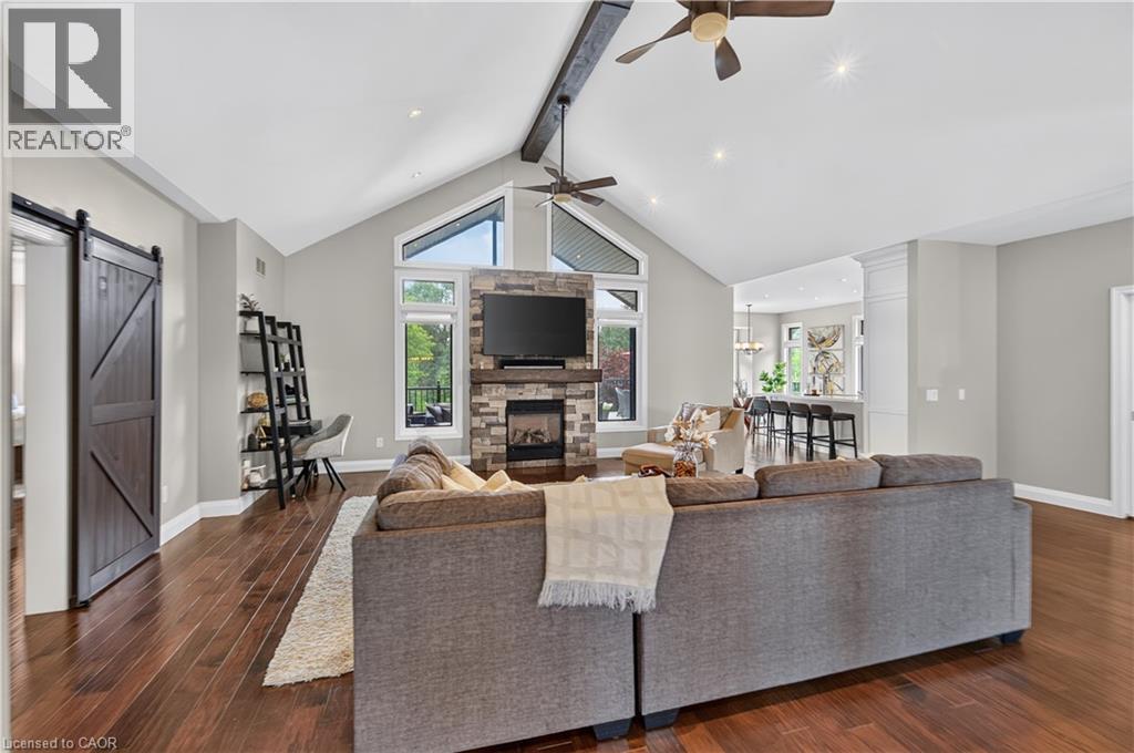 Spacious living area featuring rich wood-finish flooring and vaulted ceilings with exposed beam accents - 2050 15 Side Road, Milton, ON - Indoor Photo Showing Living Room With Fireplace