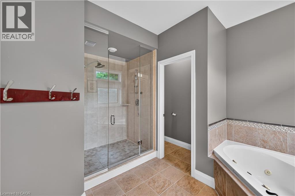 Bathroom featuring a glass-enclosed shower, a built-in corner soaking tub with tiled surround, and ceramic tile flooring - 2050 15 Side Road, Milton, ON - Indoor Photo Showing Bathroom