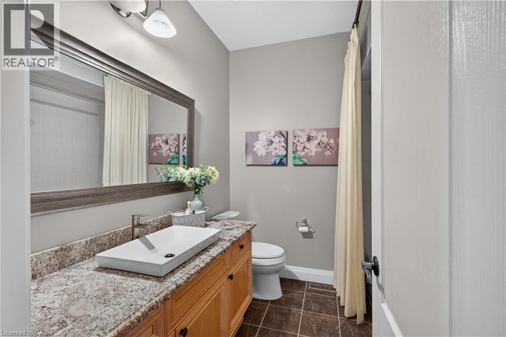 Bathroom featuring a wood vanity with a stone countertop, vessel sink, and a framed mirror - 2050 15 Side Road, Milton, ON - Indoor Photo Showing Bathroom