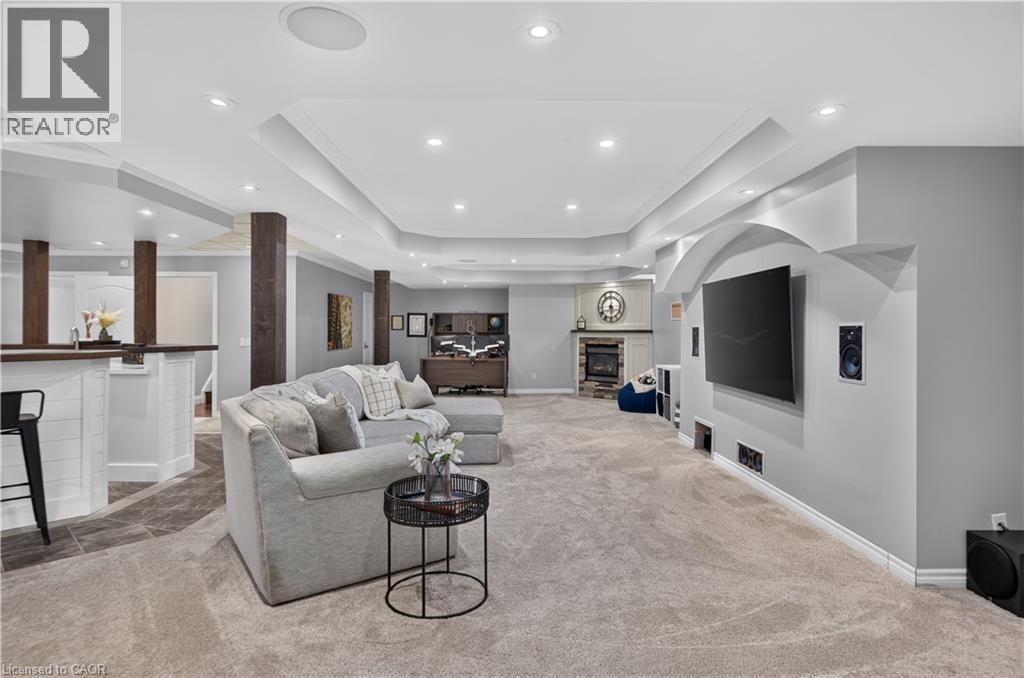 Spacious entertainment area featuring recessed lighting, a built-in fireplace with a stone surround, and carpet flooring - 2050 15 Side Road, Milton, ON - Indoor